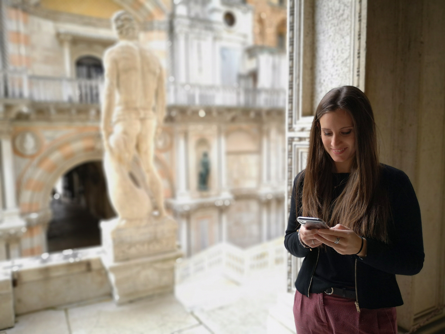 una ragazza guarda il cellulare a palazzo ducale